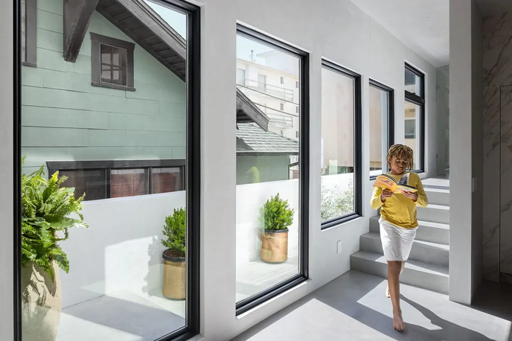 Interior shot of a kind walking barefoot in front of picture window .